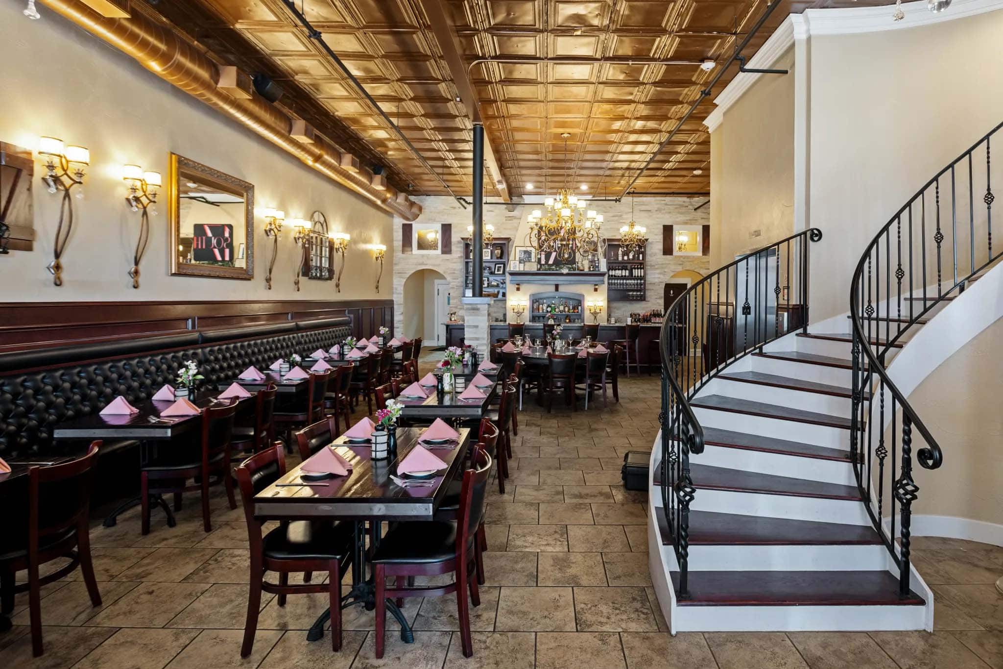 Elegant restaurant interior with dining tables, chandeliers, and a staircase in Temple, Texas.